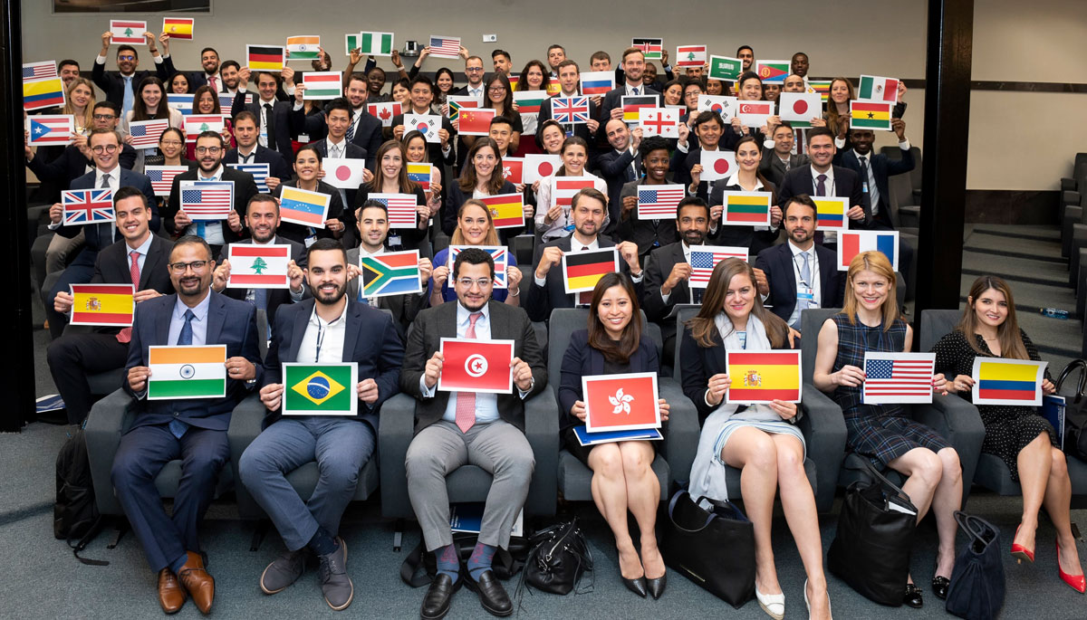 Class photo showing around 70 students holding papers showing the flags of their home countries